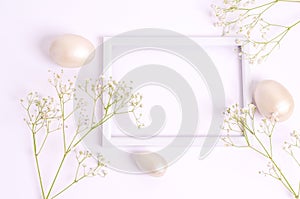 Easter mother-of-pearl eggs and hepsophila flowers around a frame on a white background