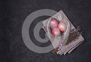 Easter multicolored pastel pink eggs in a glass bowl on a dark background. Flat lay. Easter and spring holiday concept.