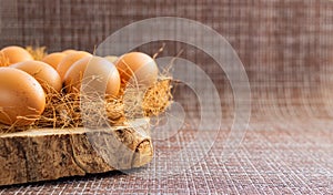 Easter, organic healthy food concept with copy space. Brown eggs on cross section of tree trunk with wicker background.