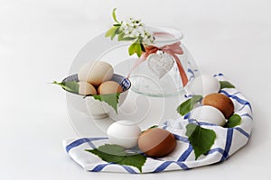 Easter - pascha, white and beige egg on blue-white tablecloth, in the background blooming twig in vase