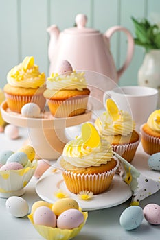 Easter pastry lemon cupcakes with yellow buttercream frosting decorated with sprinkles and chocolate eggs. Festive table setting