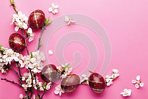 Easter pink background with Easter eggs and spring flowers. Top view with copy space