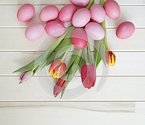 Easter. Pink easter eggs and tulips lie on a wooden background. Flat lay.