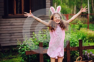 Easter portrait of happy child girl in funny bunny ears playing egg hunt outdoor