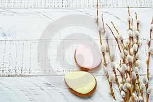 Easter. Pussy willows branches yellow ribbon and easter gingerbread hares, chickens and eggs on old wooden white background