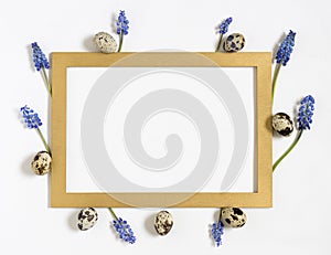 Easter quail eggs, fresh springtime flowers and golden frame.Top view, flat lay. Easter concept. Template for easter