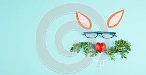 Easter rabbit face with a heart shaped nose, whiskers from carrot leaves and eyeglasse, holiday greeting card, spring season