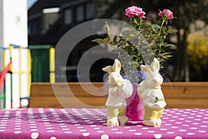 Pascua de resurrección conejos figuritas sobre el rosa mesa rosas en soleado 