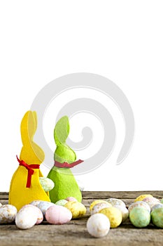 Easter rabbits on old wooden table with eggs isolated on white.