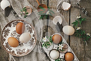 Easter rustic still life. Natural easter eggs, blooming spring flowers, burlap and spoon  flat lay on rural wooden table. Simple