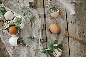 Easter rustic still life. Natural easter eggs, blooming spring flowers, feathers, burlap and spoon on rural wooden table. Happy