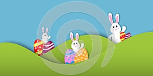 Easter`s day concept. Cute rabbits or bunny, good humored, cheerful, and colorful easter eggs with the green fields and sky