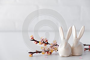 Easter spring decorative composition  with white easter ceramic bunny,  pink cherry branch. On a white background