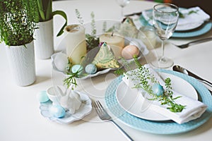 Easter and spring festive table decorated in blue and white tones in natural rustic style, with eggs, bunny, fresh flowers