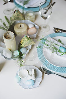 Easter and spring festive table decorated in blue and white tones in natural rustic style, with eggs, bunny, fresh flowers