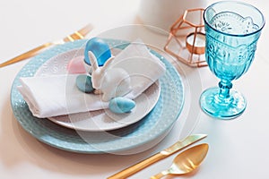 Easter and spring festive table decorated in pink and blue colours with modern golden metallic cutlery