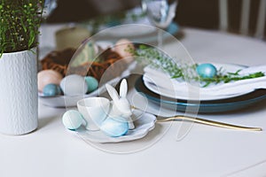 Easter and spring festive table in nordic scandinavian style, decorated in blue and white natural tones