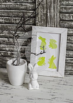 Easter still life - Easter decoration ceramic rabbit and Easter homemade picture. On a wooden rustic table.