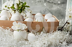 Easter still life. Gentle light photo. White eggs and delicate spring flowers of cherry