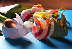 Easter still life. Paper rabbits. Easter Golden eggs. On the blue table, a bouquet of tulips