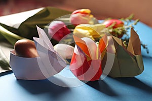 Easter still life. Paper rabbits. Origami. Easter Golden eggs. On the blue table, a bouquet of tulips