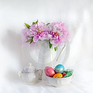 Easter still life with peonies in a vase and coloured easter eggs