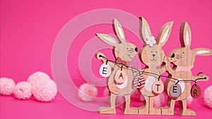 Easter stop motion animation. Beautiful Easter bunnies are moving in the frame holding the inscription Easter on a pink