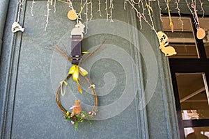 Easter street decor with carved wooden toys and garland. A wreath of willow branches stylized as an egg hangs on the