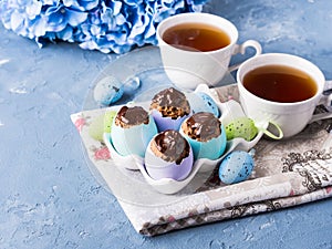 Easter sweet cup cakes treets in colorful egg shells on blue
