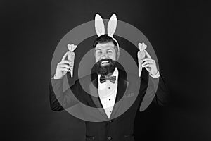 Easter symbol. Holiday celebration. Gentleman with carrot. Easter rabbit black background. Bearded man hold carrots