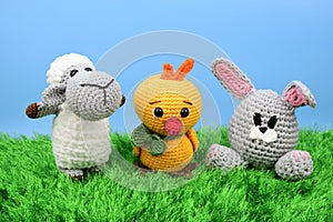 Easter symbols - lamb, chicken and rabbit standing on green grass against blue sky background