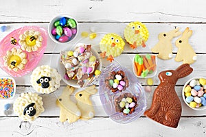 Easter table scene with assorted desserts and sweets over a white wood background