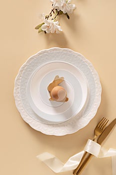 Easter table setting background with white plate, cookies, eggs and bunny