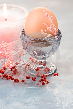 Easter table setting and decoration, egg in crystal cup,spring red and pink small flowers, burning candle