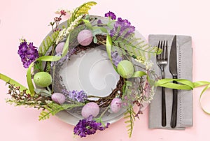 Easter table setting. Egg and flower wreath pastel color and cutlery on pink, overhead