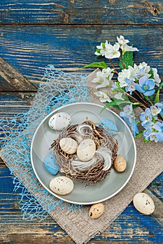 Easter table setting with eggs, bird\'s nest and blooming branch. Traditional festive symbols