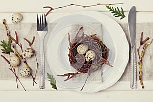 Easter table setting with eggs and spring decoration on rustic background, vintage toning photo