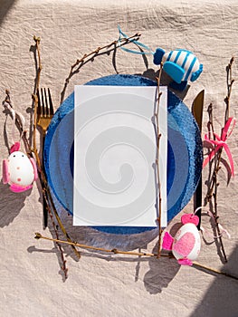 Easter table setting empty blue glass plate cutlery tree branches linen cloth flat lay harsh shadow Festive dish place