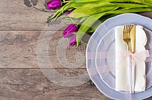 Easter table setting, flatlay - wedding party, event decoration. Purple dishes and a gold fork and a spoon on a wooden background