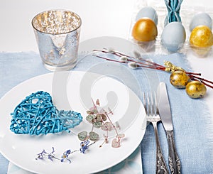 Easter table setting with gold and blue eggs and cutlery. Holidays background.
