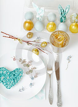 Easter table setting with gold and blue eggs and cutlery. Holidays background.