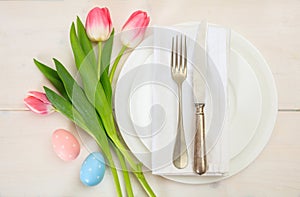 Easter table setting with pink tulips on white wooden background