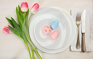 Easter table setting with pink tulips on white wooden background