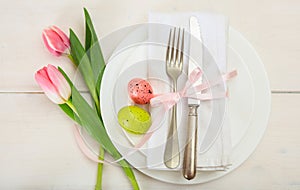 Easter table setting with pink tulips on white wooden background