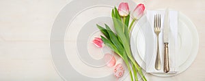 Easter table setting with pink tulips on white wooden background. Top view, copy space, banner