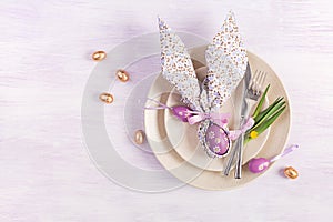 Easter table setting. White plate with a napkin folded in the shape of a rabbit