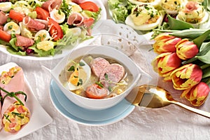 Easter table with traditional soup white borscht and fresh salads