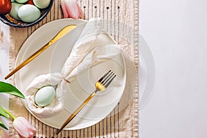 Easter themed table setting, with napkin folded in shape of a rabbit and blue egg