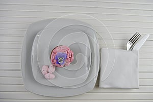 Easter time table place setting in white and decorated with pink speckled eggs and a cupcake with edible flower