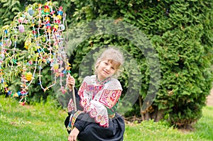 Easter traditional folk costume complimenting on Easter with colorful eggs hang on green branch